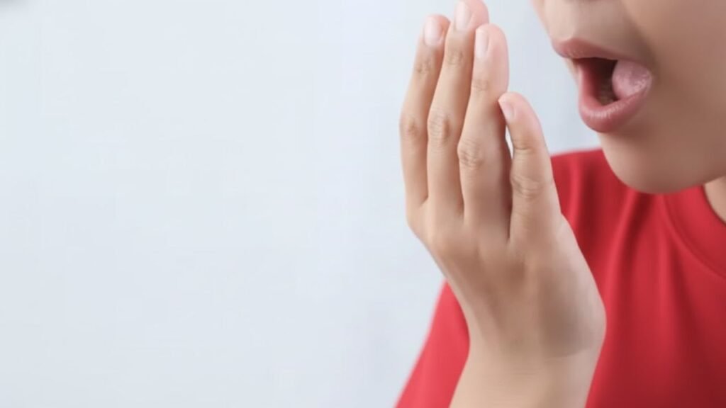 paciente sentindo um forte mau hálito vindo da sua boca por conta da faceta de resina mal feita